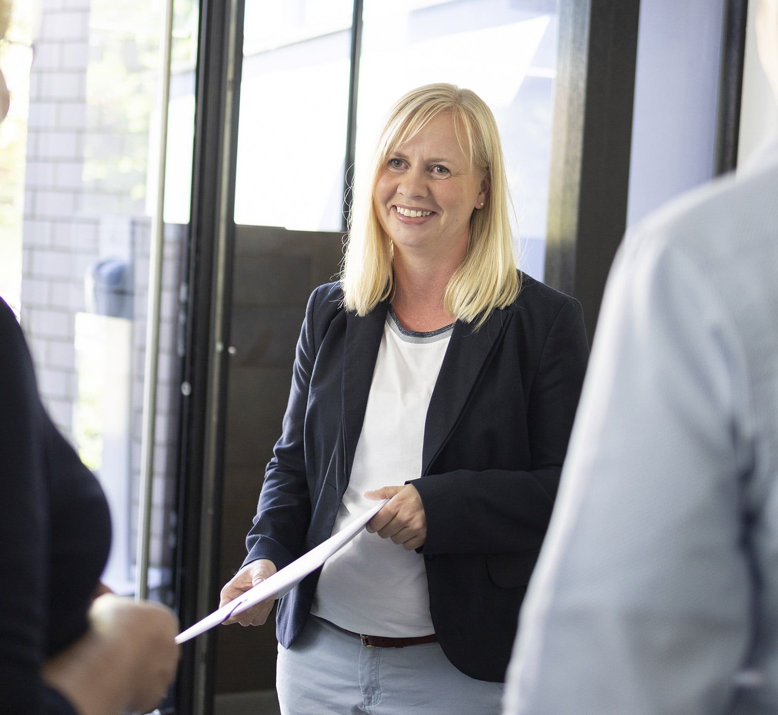 Eine Mitarbeiterin steht in einer Gesprächsrunde und lächelt