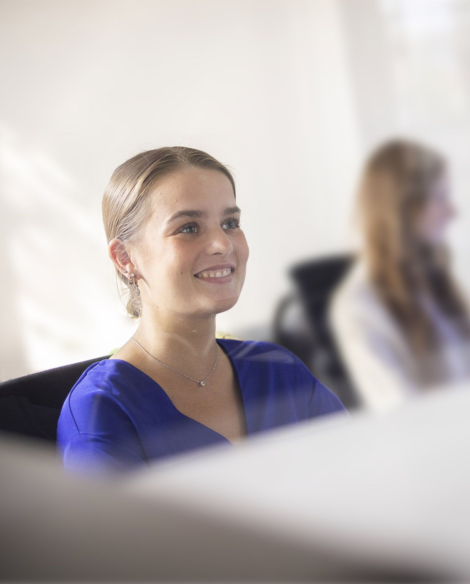 Eine Mitarbeiterin sitzt am Schreibtisch und lächelt
